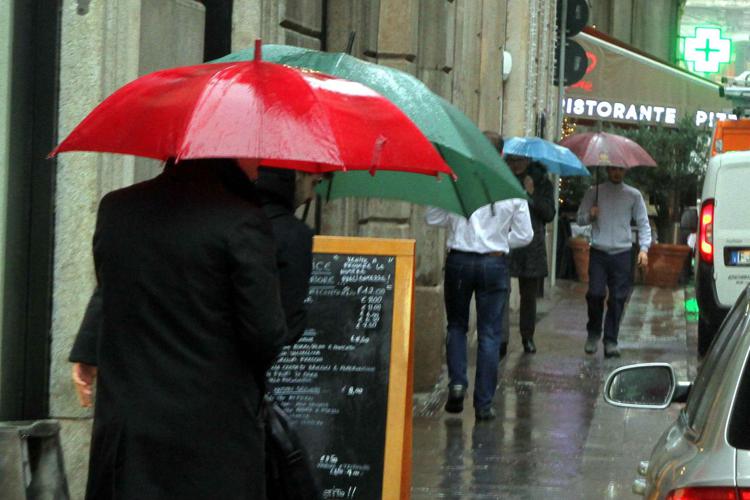 Persone si riparano dalla pioggia con ombrelli - (Fotogramma)