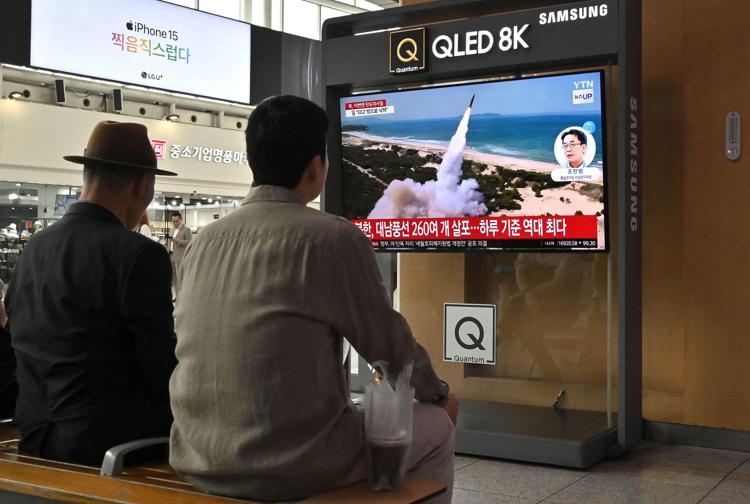 Persone guardano uno schermo televisivo che mostra un notiziario con filmati di un test missilistico nordcoreano - (Afp)