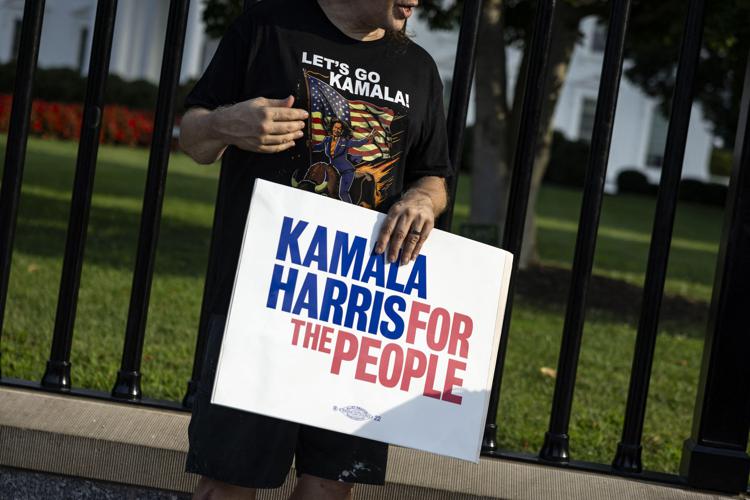 Un uomo che indossa una maglietta 'Let's Go Kamala' tiene un cartello a sostegno della vicepresidente degli Stati Uniti Kamala Harris davanti alla Casa Bianca a Washington - (Afp)