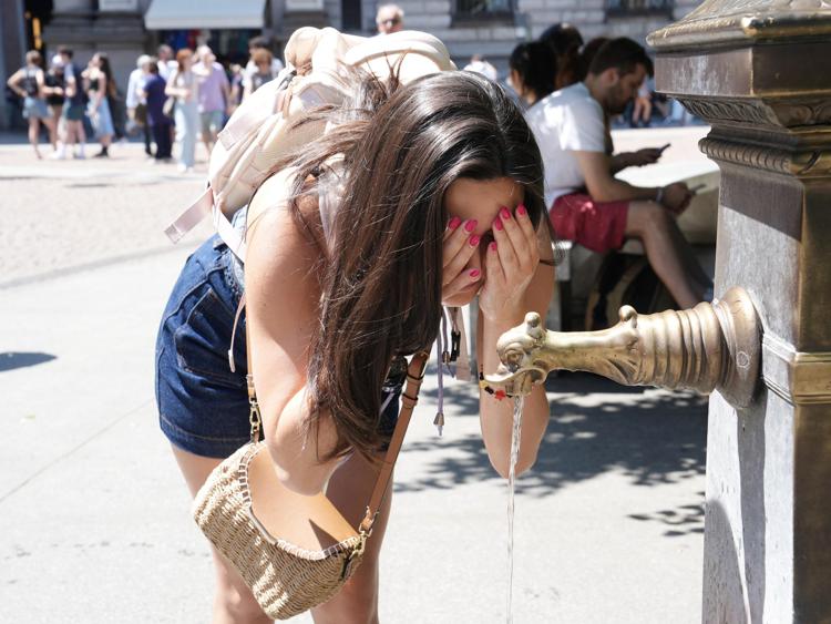 Una ragazza cerca di rinfrescarsi ad una fontanella