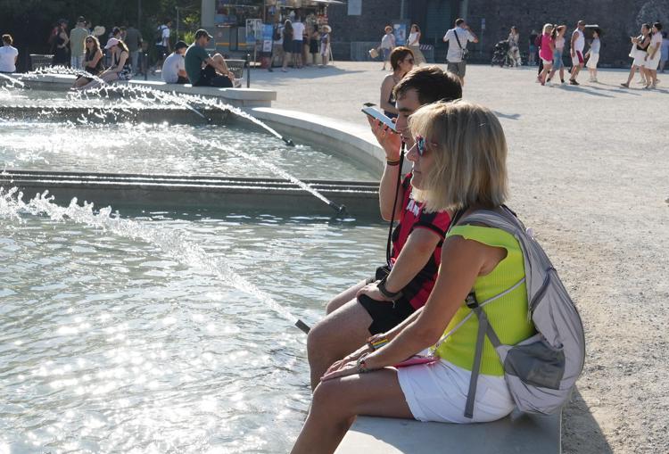 Turisti con i piedi nella fontana per rinfrescarsi dal caldo (Fotogramma/Ipa)