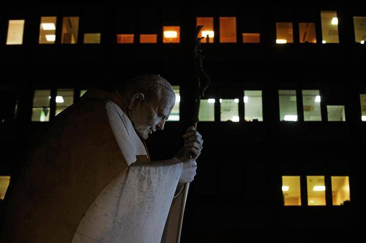 Il Policlinico Gemelli con le finestre della stanza del Papa illuminate e la statua di Wojtyla in primo piano  - Fotogramma